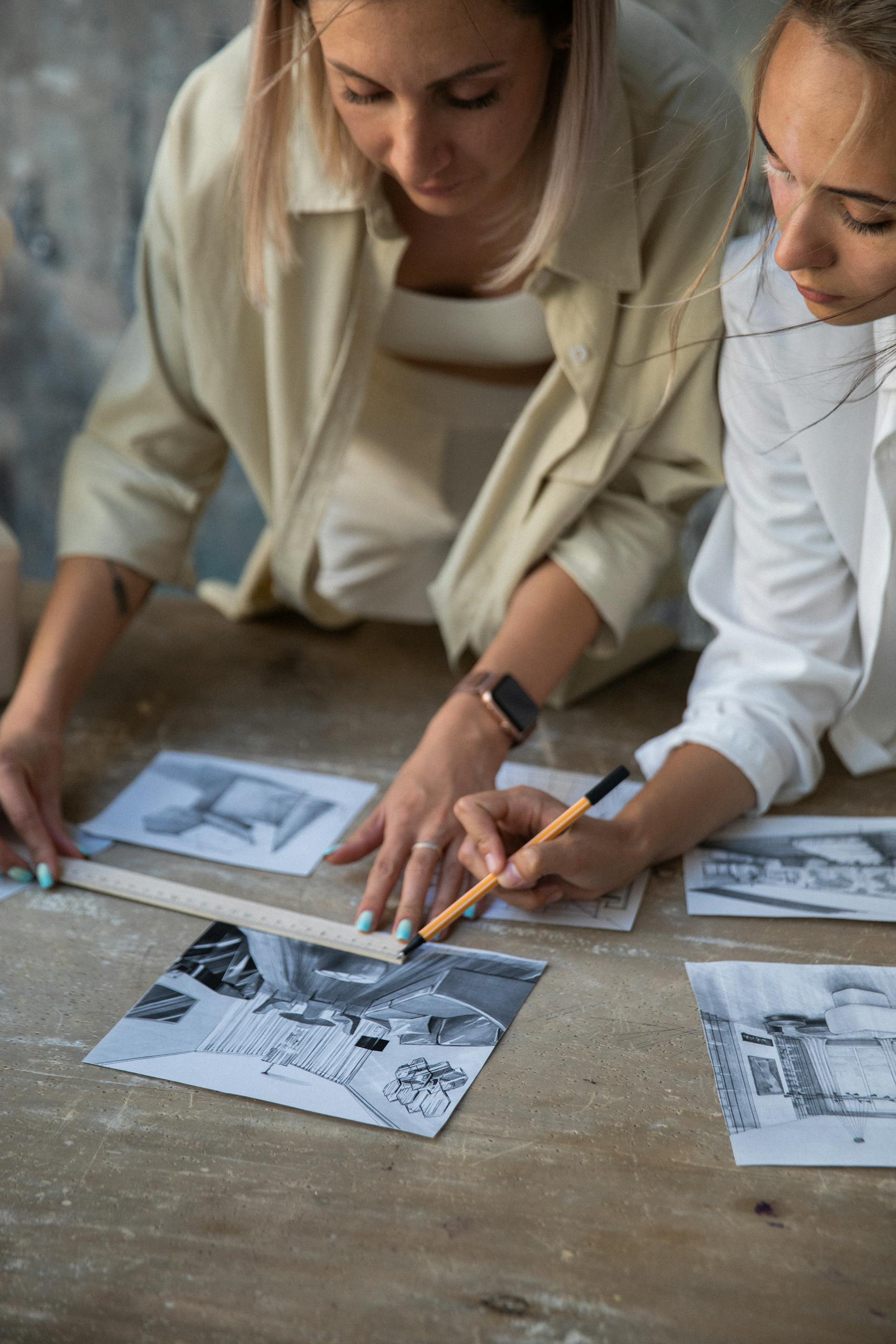 Two women working together on a creative design project, analyzing sketches in a collaborative setting.